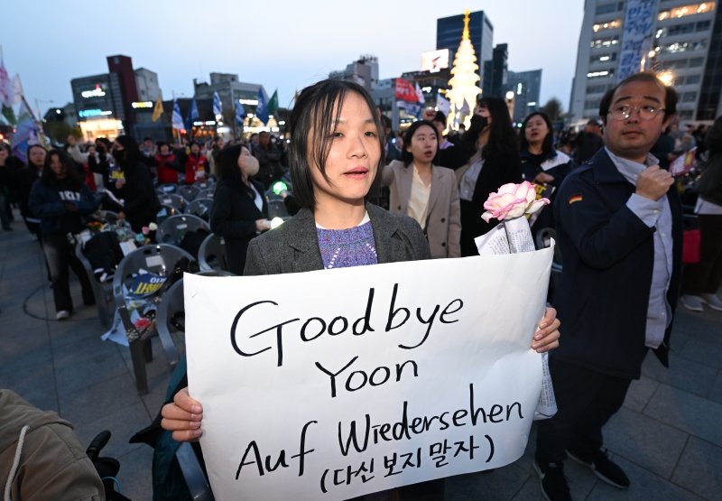 [광주=뉴시스] 김혜인 기자 = 윤석열 대통령이 파면된 4일 오후 광주 동구 5·18민주광장에서 열린 광주시민 승리대회에서 한 참석자가 파면 환영 문구를 들고 있다. 2025.04.04.hyein0342@newsis.com