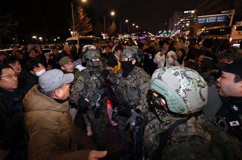 지난해 12월 3일 윤석열 대통령이 비상계엄령을 전격 선포한 뒤 여의도 국회 앞에서 시민들이 경내로 진입하려는 계엄군을 붙잡아 막아서고 있다. 2024.12.4/뉴스1 ⓒ News1 구윤성 기자