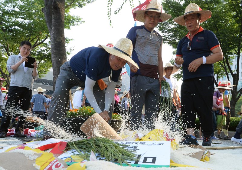 전국농민대회에 참가자들이 31일 오후 서울 세종로 정부서울청사 앞에서 밥쌀 수입 중단 촉구하며 미국산 쌀포대를 망치로 내리치고 있다. 농민들은 정부가 작년 9월 세계무역기구(WTO)에 쌀 관세화를 통보해 쌀 수입에 대한 의무가 끝났음에도 밥쌀 수입을 강행하고 있다며 밥쌀 수입을 중단하고 농민생존권을 보장하라고 촉구했다. 2015.7.31/뉴스1 ⓒ News1 신웅수 기자