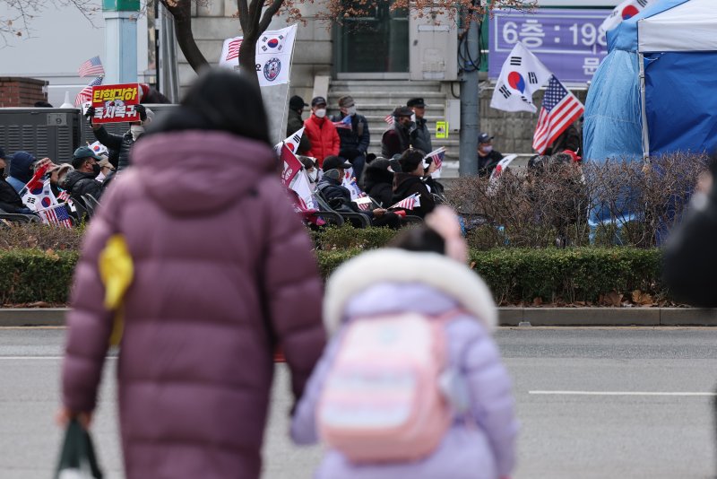 윤석열 대통령 탄핵심판의 선고일이 임박한 가운데 18일 오후 서울 종로구 헌법재판소 인근 학교에 재학중인 초등학생들이 탄핵반대 시위대를 바라보며 하교하고 있다. .2025.3.18/뉴스1 ⓒ News1 오대일 기자