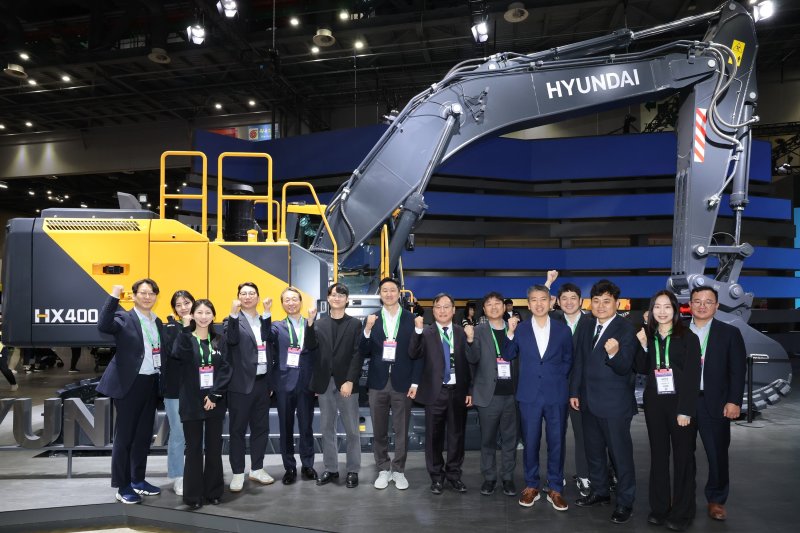 2025서울모빌리티쇼 HD현대관을 방문한 정기선 HD현대 수석부회장(왼쪽에서 7번째)이 차세대 신모델 굴착기 앞에서 조영철 HD현대사이트솔루션 사장(왼쪽에서 5번째) 및 직원들과 기념사진을 촬영하고 있다.(HD현대 제공)