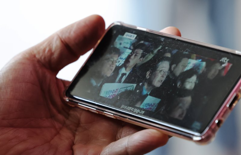 10일 오전 서울 중구 서울역을 찾은 시민이 스마트폰을 통해 이재명 전 더불어민주당 대표의 대통령 선거 출마 선언 영상을 바라보고 있다. 2025.4.10/뉴스1 ⓒ News1 장수영 기자