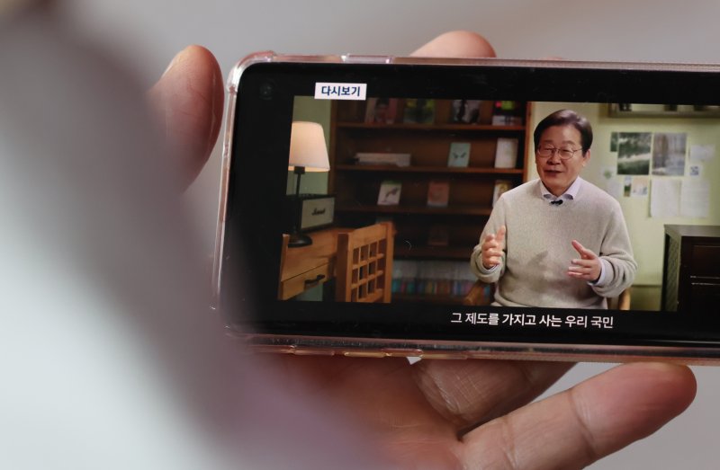 10일 오전 서울 중구 서울역을 찾은 시민이 스마트폰을 통해 이재명 전 더불어민주당 대표의 대통령 선거 출마 선언 영상을 바라보고 있다. 2025.4.10/뉴스1 ⓒ News1 장수영 기자