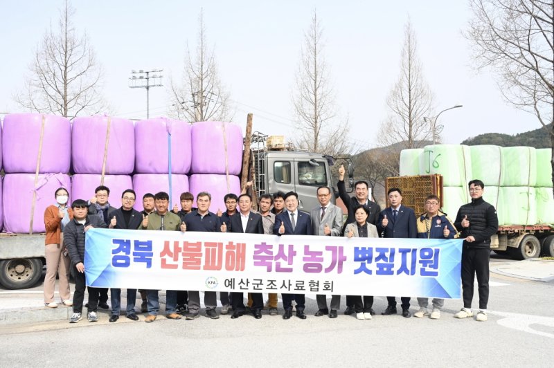 예산 조사료협회 등 관계자들이 경북 산불 피해 축산농가 지원 볏짚 앞에서 기념촬영을 하고 있다. (예산군 제공. 재판매 및 DB금지)/뉴스1