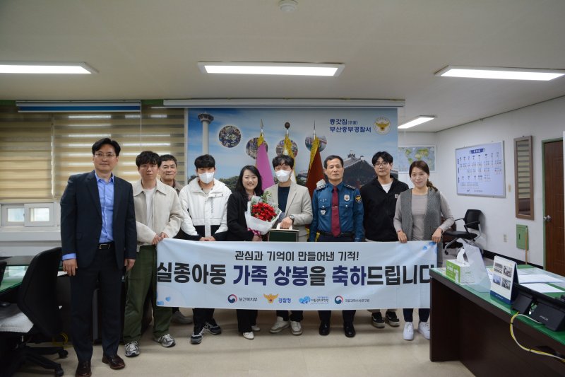 A 씨와 그의 누나가 각각 케이크와 꽃을 들고 50년만에 재회한 기념으로 부산중부경찰서 관계자들과 사진을 찍고 있다.(부산 중부경찰서 제공. 재판매 및 DB 금지)