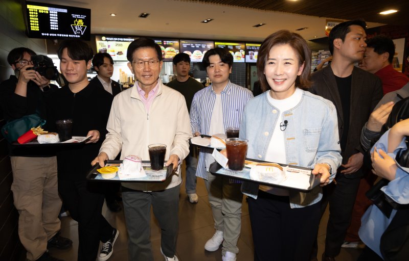 [서울=뉴시스] 황준선 기자 = 제21대 대통령선거 출마를 선언한 김문수 전 고용노동부 장관과 나경원 국민의힘 의원이 12일 오후 서울 동작구 맥도날드 중앙대학교점에서 학생들과 햄버거를 들고 이동하고 있다. 2025.04.12. hwang@newsis.com