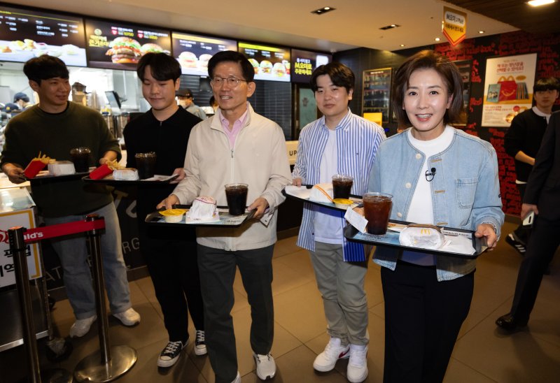 [서울=뉴시스] 황준선 기자 = 제21대 대통령선거 출마를 선언한 김문수 전 고용노동부 장관과 나경원 국민의힘 의원이 12일 오후 서울 동작구 맥도날드 중앙대학교점에서 학생들과 햄버거를 들고 이동하고 있다. 2025.04.12. hwang@newsis.com