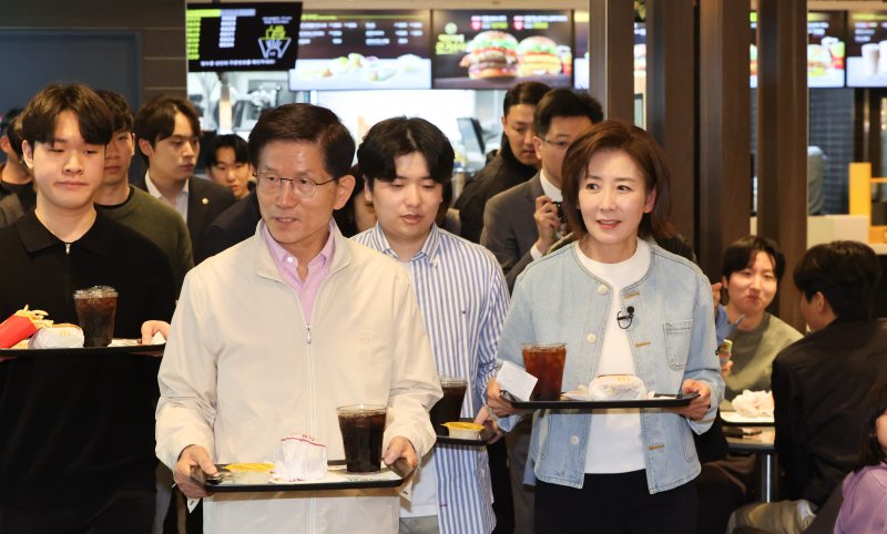[서울=뉴시스] 황준선 기자 = 제21대 대통령선거 출마를 선언한 김문수 전 고용노동부 장관과 나경원 국민의힘 의원이 12일 오후 서울 동작구 맥도날드 중앙대학교점에서 학생들과 햄버거를 들고 이동하고 있다. 2025.04.12. hwang@newsis.com