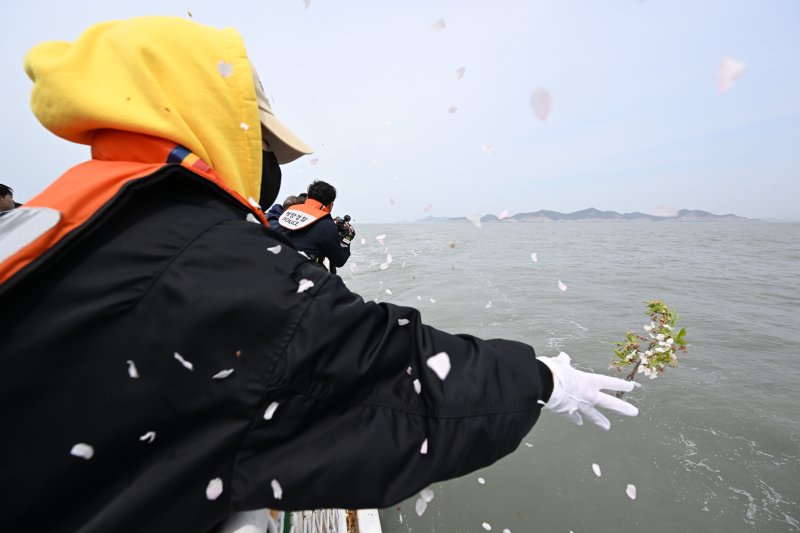 [진도=뉴시스] 김혜인 기자 = 세월호 참사 11주기인 16일 오전 전남 진도군 맹골수도에서 열린 선상추모식 중 세월호 참사 유족이 희생자를 기리며 벚꽃을 바다에 던지고 있다. 이 꽃은 희생자들이 다닌 단원고등학교 교정에 핀 벚꽃이다. 2025.04.16. hyein0342@newsis.com