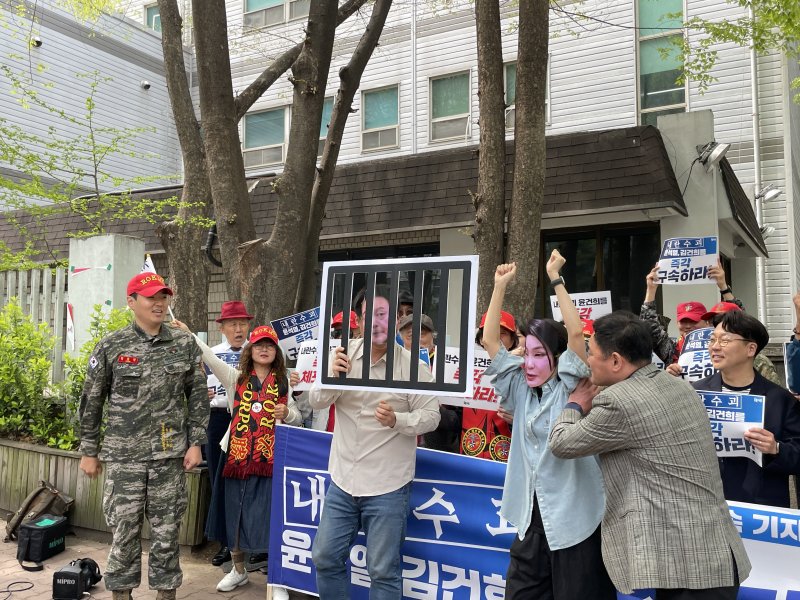 [서울=뉴시스]최은수 기자=촛불행동, 해병대 예비역 연대 등 9개 시민단체가 18일 오전 서울 서초구 서울회생법원 앞에서 윤석열 전 대통령 부부 구속을 촉구하는 기자회견을 열었다. 사진은 윤 전 대통령과 김씨를 형상화한 피켓을 감옥에 넣는 퍼포먼스를 벌이는 모습. 2025.04.18