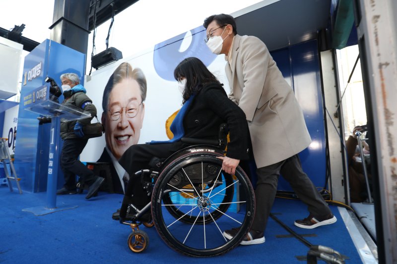 이재명 더불어민주당 대선 경선 후보가 지난 대선 시절인 2022년 2월 23일 오후 세종시 나성동 먹자골목에서 열린 '김대중-노무현 대통령의 꿈이 깃든 세종시, 균형발전 꼭 이루겠습니다' 세종 유세에서 휠체어 장애인 김지혜 씨와 함께 리프트에 탑승하고 있다. 2022.2.23/뉴스1 ⓒ News1 오대일 기자