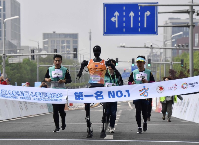 [베이징=신화/뉴시스] 19일 중국 베이징 이좡 경제기술개발구에서 열린 휴머노이드 로봇 하프마라톤에서 우승한 로봇 '톈궁 울트라'가 참가팀 인원들과 함께 달리고 있다. 2025.04.20