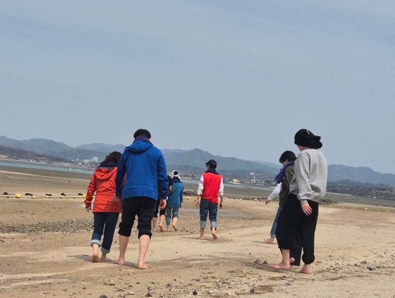지난 16일부터 이틀간 밀알복지재단은 13명의 시각, 청각 또는 시청각 장애인(장애 당사자), 활동지원사들과 함께 '오감만족 여행'을 진행했다. 전남 함평 돌머리해수욕장을 거니는 당사자들과 활동지원사들의 모습. 2025.4.17/뉴스1 ⓒ News1 남해인 기자