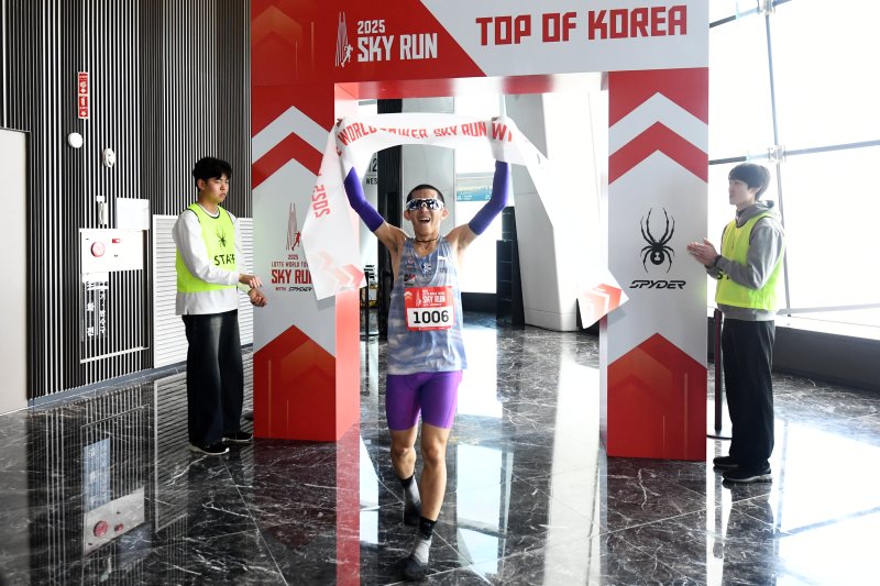 [서울=뉴시스] 황준선 기자 = 20일 오전 서울 송파구 롯데월드타워에서 열린 '2025 롯데월드타워 스카이런 with SPYDER'에서 참가자가 결승선을 통과한 뒤 메달을 받고 있다.(공동취재) 2025.04.20. photo@newsis.com