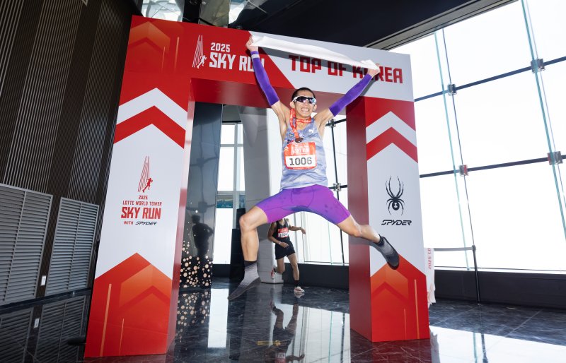 [서울=뉴시스] 황준선 기자 = 20일 오전 서울 송파구 롯데월드타워에서 열린 '2025 롯데월드타워 스카이런 with SPYDER'에서 참가자가 결승선을 통과한 뒤 기념촬영을 하고 있다. 2025.04.20. hwang@newsis.com