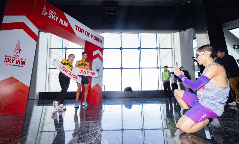 [서울=뉴시스] 황준선 기자 = 20일 오전 서울 송파구 롯데월드타워에서 열린 '2025 롯데월드타워 스카이런 with SPYDER'에서 참가자가 결승선을 통과한 뒤 기념촬영을 하고 있다. 2025.04.20. hwang@newsis.com