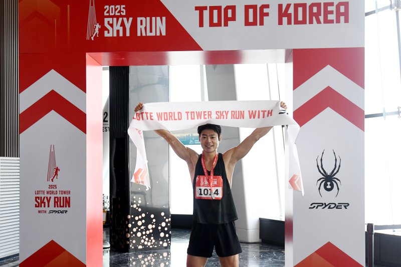 [서울=뉴시스] 황준선 기자 = 20일 오전 서울 송파구 롯데월드타워에서 열린 '2025 롯데월드타워 스카이런 with SPYDER'에서 참가자가 결승선을 통과한 뒤 기념촬영을 하고 있다.(공동취재) 2025.04.20. photo@newsis.com