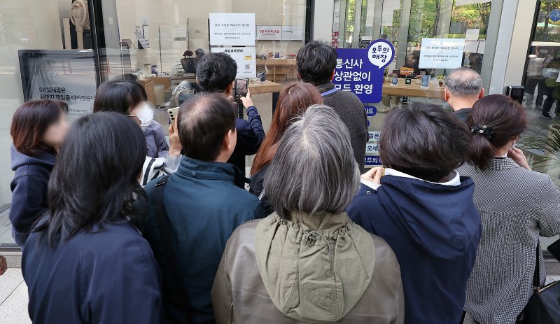 SK텔레콤 가입자 유심(USIM) 정보 해킹 사고 관련 유심 무료교체 서비스 이틀 째인 29일 오전 서울 종로구 T월드 직영 매장 앞에서 번호표를 받지 못한 고객들이 온라인 예약을 하고 있다. 2025.4.29/뉴스1 ⓒ News1 김진환 기자