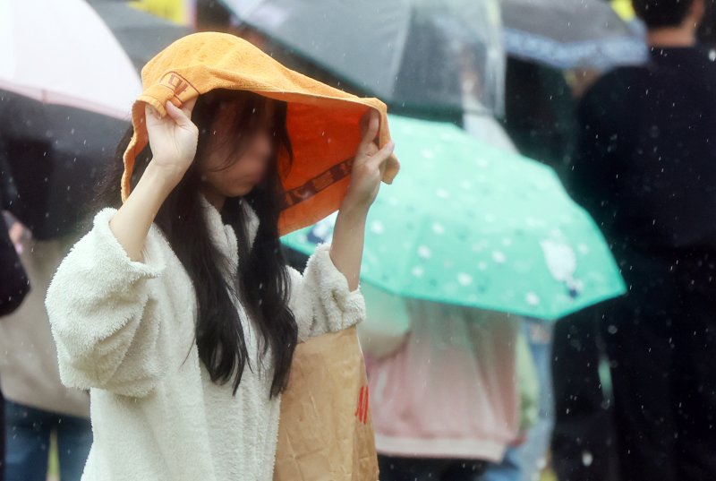 서울을 비롯한 수도권 일대에 비가 내린 1일 서울 중구 서울광장에서 한 시민들이 수건으로 비를 피하며 발걸음을 옮기고 있다. 2025.5.1/뉴스1 ⓒ News1 김진환 기자