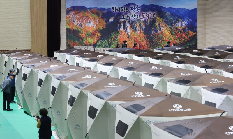 [청송=뉴시스] 김금보 기자 = 경북 청송군 청송국민체육센터에 마련된 산불 대피소 이재민 텐트 뒤로 산불피해를 입기전 주왕산 사진이 보이고 있다. 2025.03.28. kgb@newsis.com