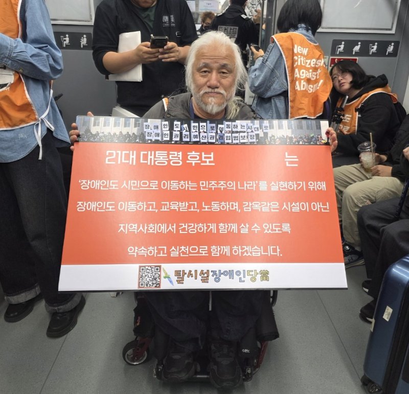 [서울=뉴시스] 고재은 수습 기자 = 박경석 전국장애인차별철폐연대(전장연) 상임공동대표가 2일 오전 서울 지하철 4호선 열차 안에서 21대 대통령 선거 후보에게 장애인권리정책을 요구하는 피켓을 들고 있다. 같은 날 전장연은 서울 종로구 지하철 4호선 혜화역에서 지하철 탑승 선전전을 멈추고 서울 영등포구 국회로 이동했다. 2025.05.02. jeko@newsis.com
