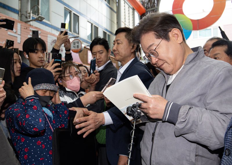 '골목골목 경청투어 : 동해안벨트편'에 나선 이재명 더불어민주당 대통령 후보가 3일 오전 강원 양양군 양양시장에서 한 시민 요청으로 책에 서명하고 있다. 2025.5.3/뉴스1 ⓒ News1 이재명 기자