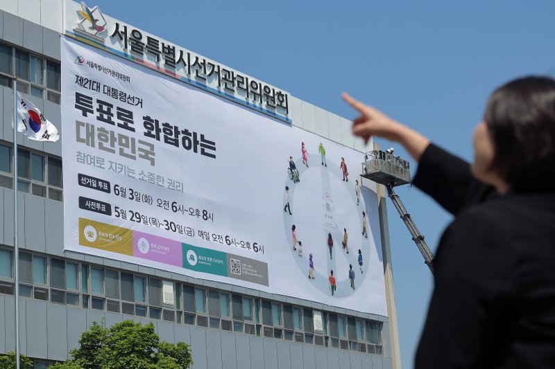 29일 오후 서울 종로구 창경궁로 서울시선거관리위원회 외벽에 관계자들이 제21대 대통령 선거 대형 홍보 현수막을 게시하고 있다. 제21대 대통령 선거는 오는 6월 3일 치러진다. 2025.4.29/뉴스1 ⓒ News1 박정호 기자
