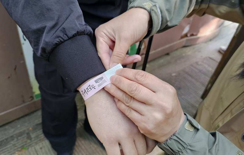 [제주=뉴시스] 임재영 기자 = 4일 오전 한라산국립공원 관음사탐방로 입구에서 탐방객에게 정상 탐방을 인증하는 '띠지'를 손목에 부착하고 있다. 2025.05.04. ijy788@newsis.com