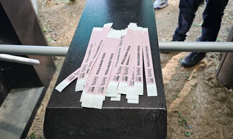 [제주=뉴시스] 임재영 기자 = 4일 오전 한라산국립공원 관음사탐방로 입구에서 탐방객에게 나눠주고 있는 '띠지'. 2025.05.04. ijy788@newsis.com