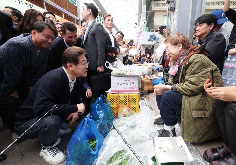 [영월=뉴시스] 조성봉 기자 = 민심을 청취하는 '경청 투어'에 나선 이재명 더불어민주당 대선후보가 4일 강원 영월서부시장에서 상인에게 나물을 구매하며 대화를 하고 있다.2025.05.04. suncho21@newsis.com