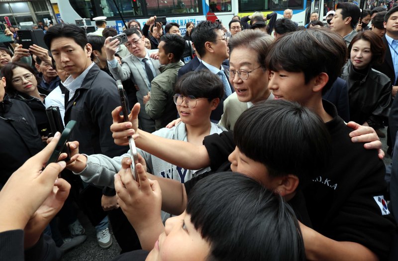 [옥천=뉴시스] 조성봉 기자 = 민심을 청취하는 '경청 투어'에 나선 이재명 더불어민주당 대선후보가 6일 충북 옥천군 옥천공설시장에서 어린이들과 셀카를 찍고 있다. 2025.05.06. suncho21@newsis.com