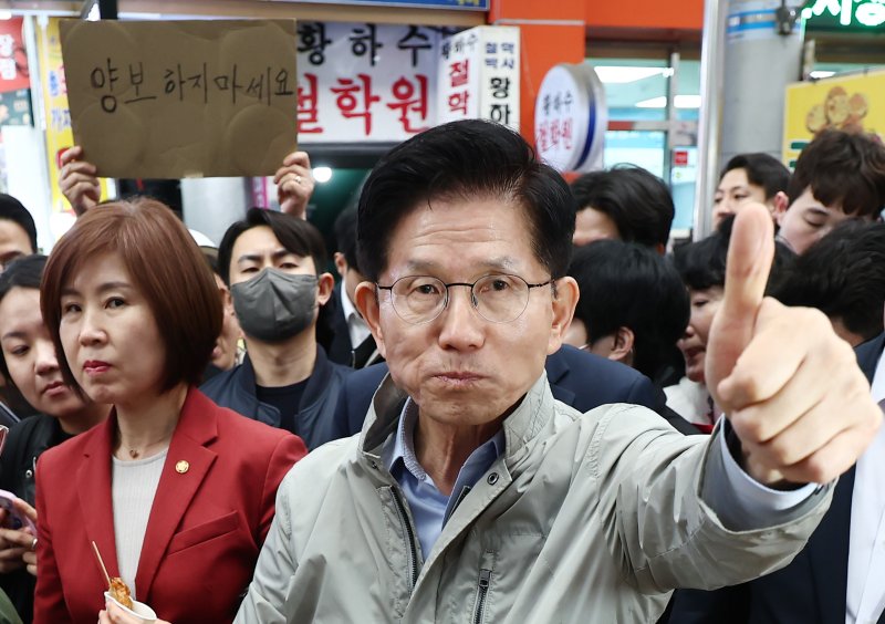 김문수 국민의힘 대통령 후보가 6일 경북 포항시 죽도시장에서 구매한 어묵을 먹으며 엄지를 치켜세우고 있다. 뒷편으로는 한 지지자가 '양보 하지 마세요'라고 적힌 종이를 들어보이고 있다. 2025.5.6/뉴스1 ⓒ News1 김민지 기자