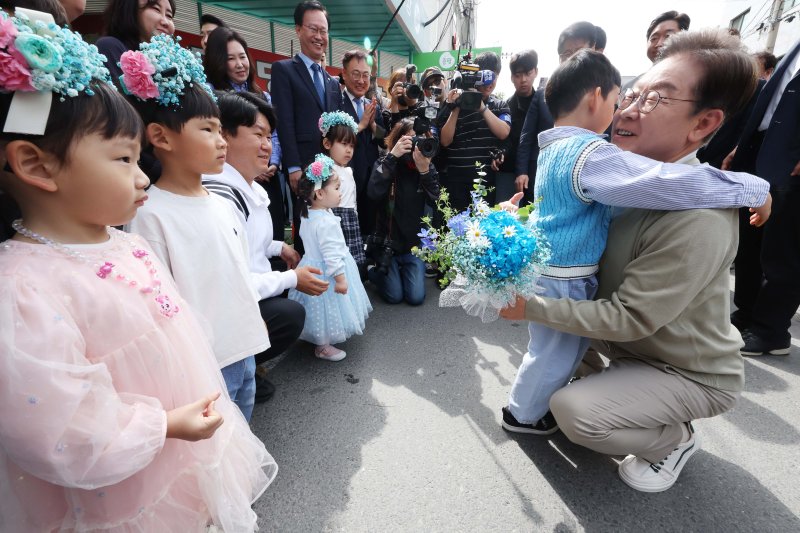 [증평=뉴시스] 조성봉 기자 = 민심을 청취하는 '경청 투어'에 나선 이재명 더불어민주당 대선후보가 6일 충북 증평군 장뜰시장 입구에서 어린이들에게 꽃다발을 선물 받고 있다.2025.05.06. suncho21@newsis.com