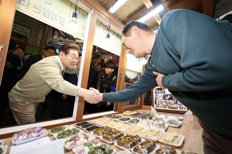 [영동=뉴시스] 조성봉 기자 = 민심을 청취하는 '경청 투어'에 나선 이재명 더불어민주당 대선후보가 6일 충북 영동군 영동전통시장에서 떡가게 상인과 인사를 하고 있다.2025.05.06. suncho21@newsis.com