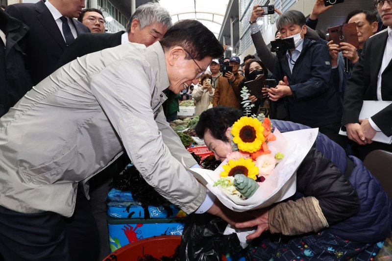 [포항=뉴시스] 권창회 기자 = 김문수 국민의힘 대선 후보가 6일 경북 포항시 죽도시장을 방문해 상인들에게 꽃다발을 선물하고 있다. 2025.05.06. kch0523@newsis.com