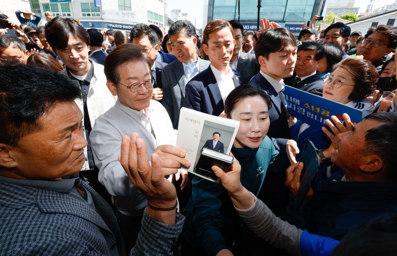 [임실=뉴시스] 조성봉 기자 = 민심을 청취하는 '경청 투어'에 나선 이재명 더불어민주당 대선후보가 7일 전북 임실군 임실전통시장에서 시민들에게 사인 요청을 받고 있다. (공동취재) .2025.05.07. photo@newsis.com