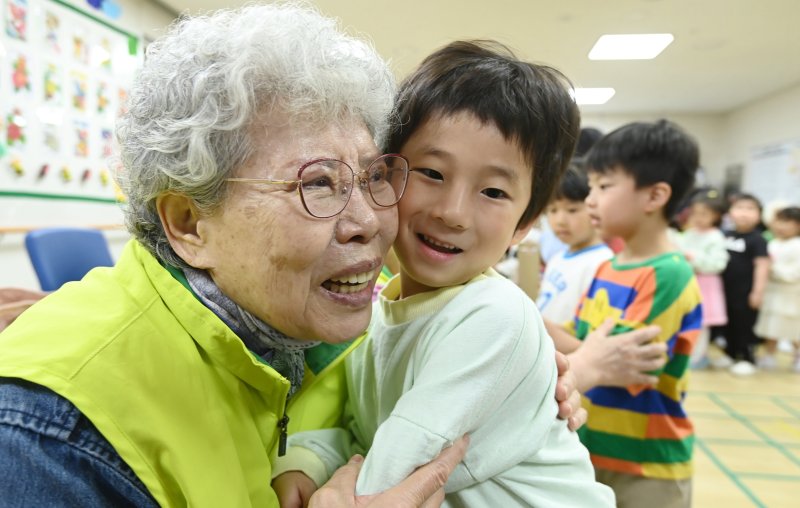 [수원=뉴시스] 김종택 기자 = 어버이날을 하루 앞둔 7일 경기 수원시 팔달노인복지관을 찾은 어린이들이 고사리 손으로 어르신들에게 카네이션을 달아드린 뒤 포옹하고 있다. 2025.05.07. jtk@newsis.com