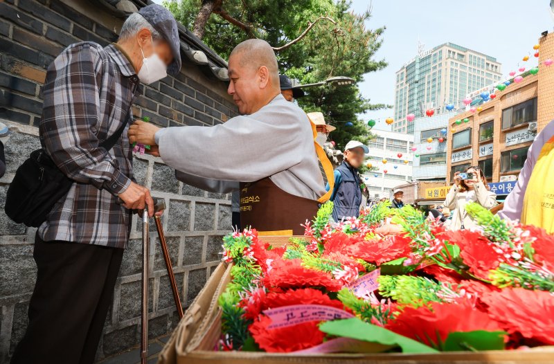 [서울=뉴시스] 황준선 기자 = 어버이날인 8일 서울 종로구 원각사 무료급식소에서 스님이 어르신들에게 카네이션을 달아드리고 있다. 2025.05.08. hwang@newsis.com