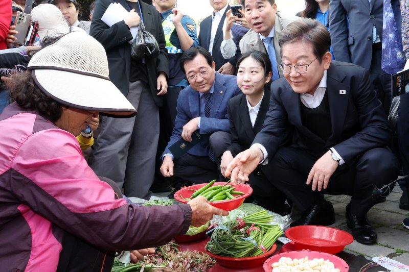 [함안=뉴시스] 조성우 기자 = 민심을 청취하는 '경청 투어'에 나선 이재명 더불어민주당 대선후보가 10일 경남 함안군 가야시장에서 한 상인에게 고추를 구매하고 있다. 2025.05.10. xconfind@newsis.com