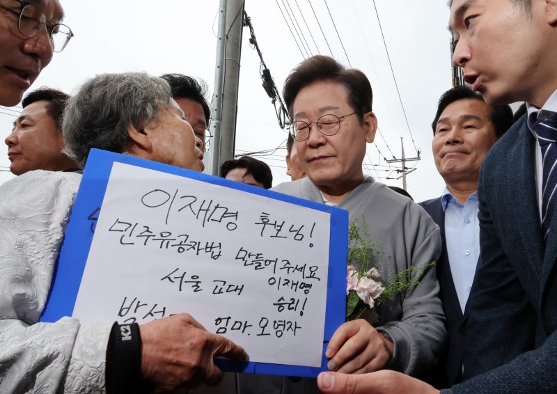 [화순=뉴시스] 조성우 기자 = 민심을 청취하는 '경청 투어'에 나선 이재명 더불어민주당 대선후보가 11일 전남 화순군 화순읍 인근 거리에서 박선영 열사 모친 오영자 씨의 민주유공자법 제정 호소 등 얘기를 듣고 있다. 2025.05.11. xconfind@newsis.com