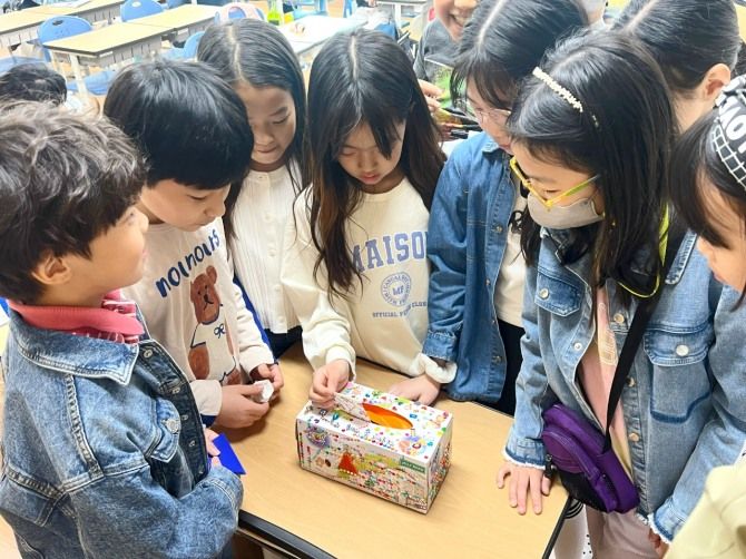 용인한얼초등학교 학생들이 교실에서 휴지곽으로 만든 모금함에 성금을 넣고 있다. 모금함에는 ‘작은 실천이 큰 변화를 만든다’는 문구가 적혀 있다. 희망브리지 제공