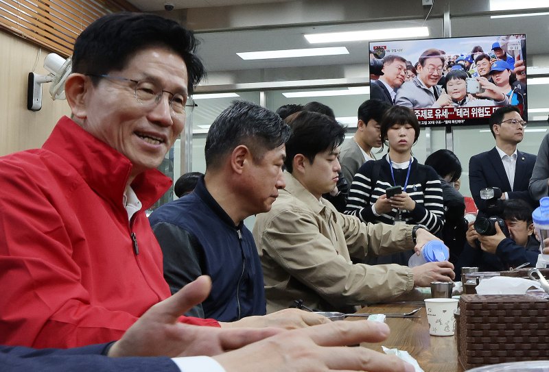 제21대 대통령 선거 공식 선거운동이 시작된 12일 새벽 서울 송파구 양재대로 가락시장에서 김문수 국민의힘 대선 후보가 상인들과 아침식사를 준비하는 가운데 식당에 진열된 텔레비전으로 이재명 더불어민주당 대선 후보 뉴스가 송출되고 있다. 2025.5.12/뉴스1 ⓒ News1 이동해 기자