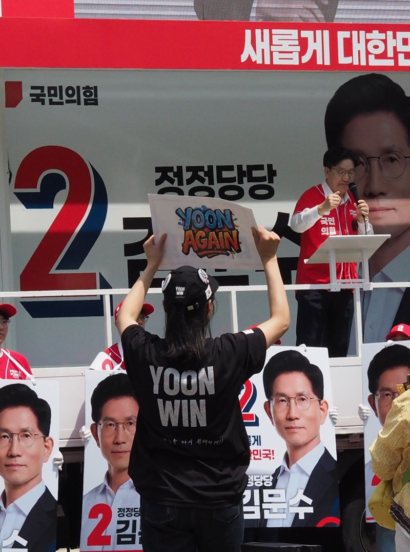 권성동 국민의힘 원내 대표가 13일 울산 남구 신정시장 앞에 설치된 유세차에 올라 김문수 대선 후보 지지연설을 하고 있는 가운데 영어로 '윤어게인'이라고 쓴 손팻말이 등장해 눈길을 끌었다. 사진=최수상 기자