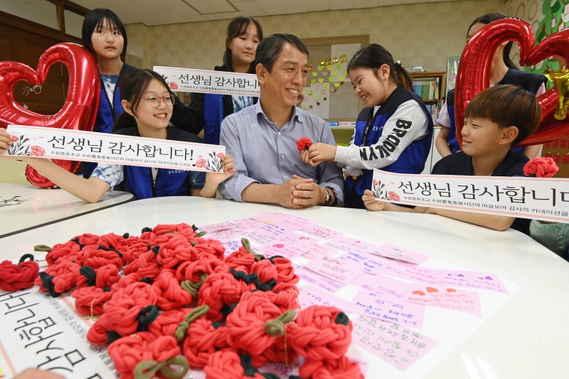 [수원=뉴시스] 김종택 기자 = 스승의 날을 하루 앞둔 14일 경기 수원시 권선구 중촌초등학교에서 통통봉사단 학생들이 직접 만든 카네이션과 감사의 편지를 선생님에게 전달하고 있다. 2025.05.14. jtk@newsis.com