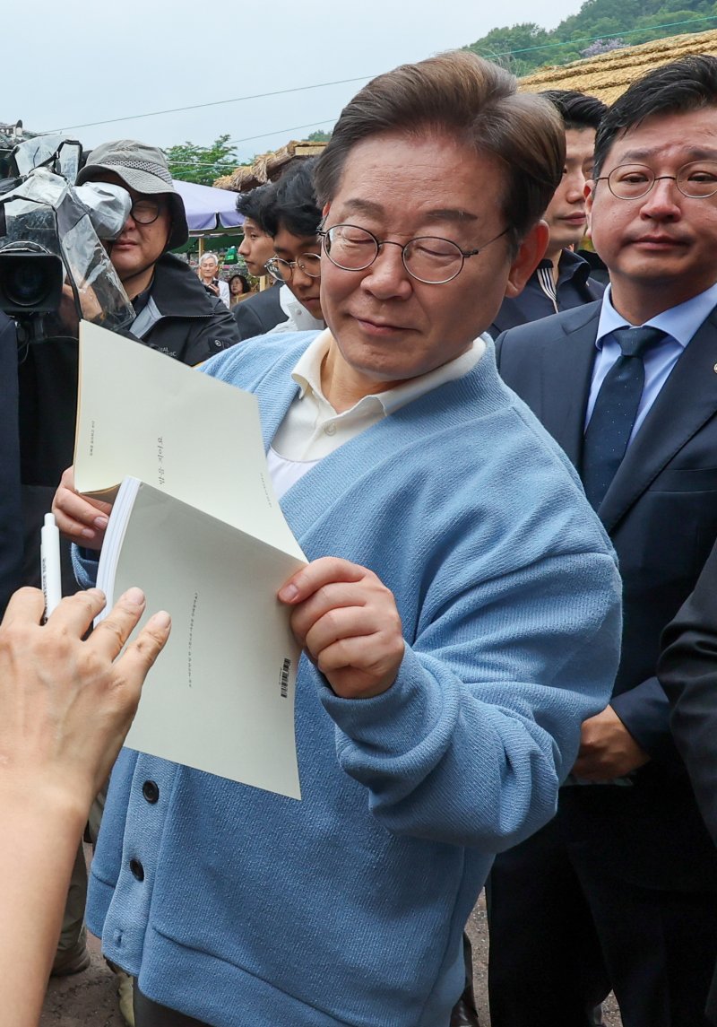 [하동=뉴시스] 권창회 기자 =이재명 더불어민주당 대선 후보가 15일 경남 하동군 화개장터 입구에서 유튜브 'K-이니셔TV 케미폭발 동서화합 화개장터 라이브'를 마치고 이동하며 지지자들에게 사인을 해주고 있다. (공동취재) 2025.05.15. photo@newsis.com