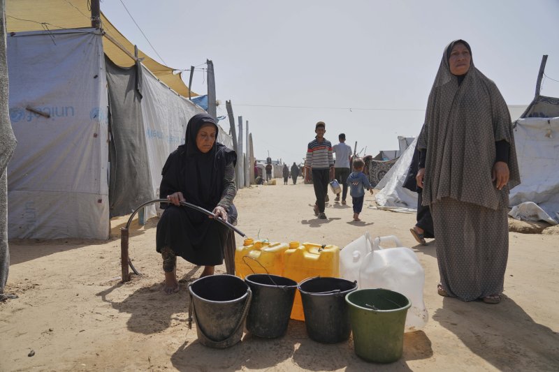 [칸유니스=AP/뉴시스] 지난 11일(현지 시간) 가자지구 칸유니스 천막촌에서 팔레스타인 난민들이 파이프에서 나오는 물을 받고 있다. 2025.05.15.