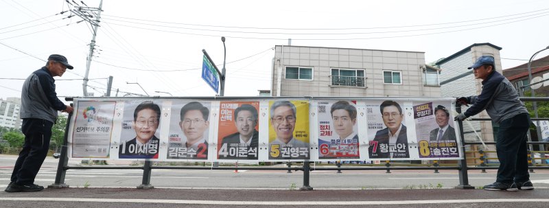 15일 경기 수원시 권선구의 한 거리에서 관계자들이 제21대 대통령선거 후보자들 선거 벽보를 부착하고 있다. 2025.5.15/뉴스1 ⓒ News1 김영운 기자