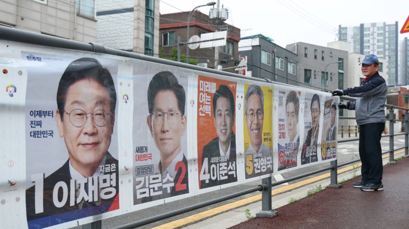 15일 경기 수원시 권선구의 한 거리에서 관계자들이 제21대 대통령선거 후보자들 선거 벽보를 부착하고 있다. 2025.5.15/뉴스1 ⓒ News1 김영운 기자