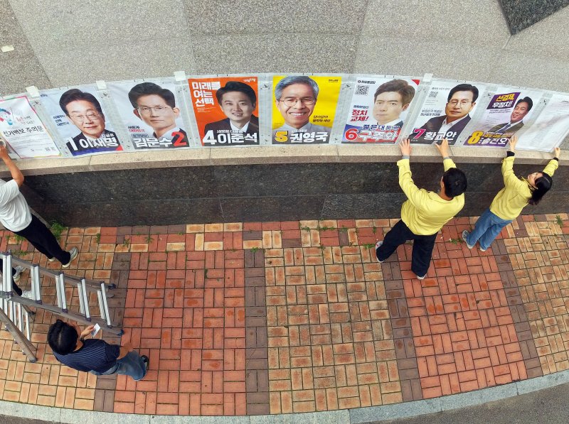 제21대 대통령 선거 벽보 부착 시작 첫날인 15일 광주 북구 운암사거리 인근에서 운암1동 행정복지센터 직원들과 관계자들이 후보자들의 벽보를 붙이고 있다.(광주 북구 제공. 재판매 및 DB 금지) 2025.5.15/뉴스1 ⓒ News1 박지현 기자