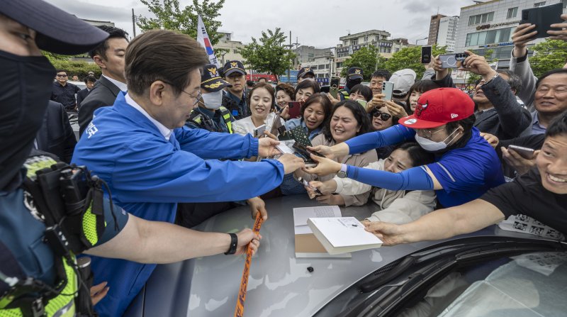 이재명 더불어민주당 대통령 후보가 16일 오전 전북 익산시 익산역 동부광장에서 유세를 마친 뒤 이동하며 지지자들에게 사인을 해주고 있다. (공동취재) 2025.5.16/뉴스1 ⓒ News1 이재명 기자